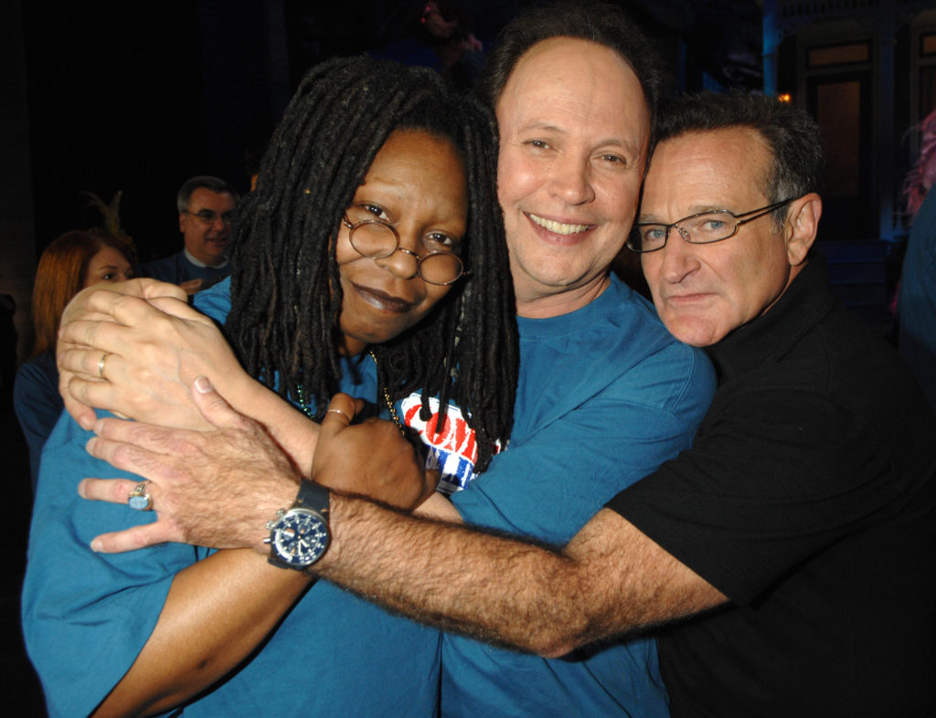 Whoopi Goldberg, Billy Crystal, and Robin Williams embracing